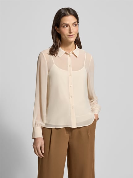 Modelka kobieta nosi Regular Fit Bluse in semitransparenter Optik od JOOP!, kremowa, półprzezroczysta, kołnierzyk koszulowy, długi rękaw, widok całej sylwetki z przodu.