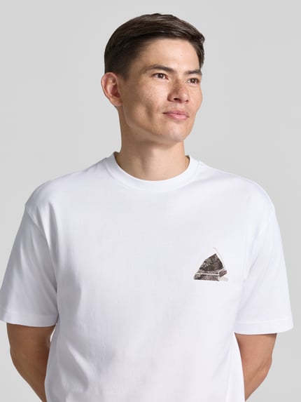 Męski model nosi Regular Fit T-Shirt aus reiner Baumwolle Modell 'TE_FRAME' von BOSS Orange, biała kolorystyka, gładka tekstura, nahaufnahme górnej części ciała.