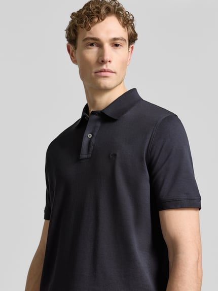 Männermodel trägt Regular Fit Poloshirt mit Logo-Stitching von Fynch-Hatton, reine Baumwolle, dunkelblau, Nahaufnahme Oberkörper.