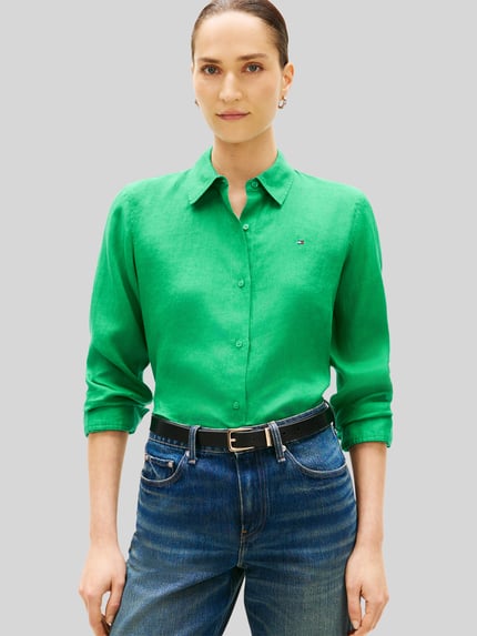 Vrouwenmodel draagt Relaxed Fit Langarmbluse aus reinem Leinen van Tommy Hilfiger in effen groene kleur met overhemdkraag, knoopsluiting, gestikt logo, lange mouw met manchet, afgeronde rompzoom, gevlamd garen, materiaal: linnen. Nahaufnahme Oberkörper.
