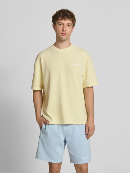 Männermodel trägt Oversized T-Shirt mit Logo-Stitching Modell 'Lagos' von Pegador in Hellgelb aus Elastischer-Material-Mix, Oversized-Fit, Herren T-Shirt, Rückenlänge bei Größe M 65 cm, Ganzkörperansicht von vorne.