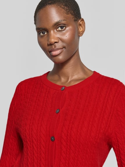 Frauenmodel trägt Regular Fit Strickjacke aus reinem Kaschmir mit Zopfmuster von Christian Berg Woman in Rot, Nahaufnahme Oberkörper.