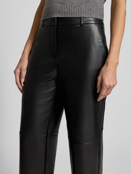 Vrouwenmodel draagt stoffen broek in leerlook van Comma, los model, steekzakken, achterzakken, binnenbeenlengte 76 cm, detailopname.