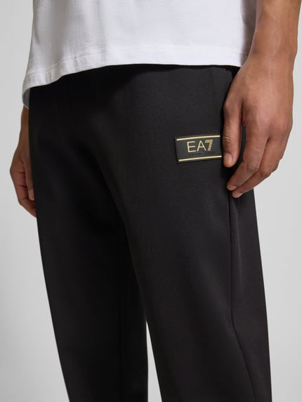 Männermodel trägt Sweatpants mit elastischem Bund und Label-Patch von EA7 Emporio Armani, Relaxed Fit, Detailaufnahme Nahaufnahme Hüfte