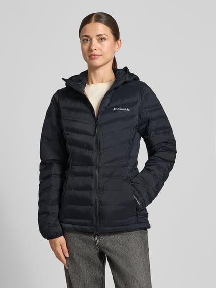 Frauenmodel trägt Jacke in Stepp-Optik Modell 'Terwilliger' von Columbia, tailliert, mit Logo-Print, Kapuze, Ganzkörperansicht von vorne.