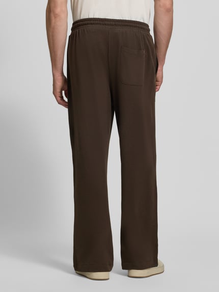Männermodel trägt braune Regular Fit Sweathose aus Baumwoll-Modal-Mix von Tommy Hilfiger, glatte Textur, Ganzkörperansicht Rückansicht. Herren Sweathose von Tommy Hilfiger