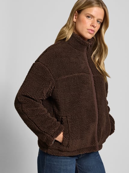 Frauenmodel trägt Teddyjacke mit Stehkragen von REVIEW in Braun mit Teddyfell-Textur, Reißverschluss, Regular Fit, Nahaufnahme Oberkörper. Damen Fleecejacke, Rückenlänge 66 cm, Schulterbreite 48 cm, Brustweite 56 cm, Ärmellänge 57 cm.