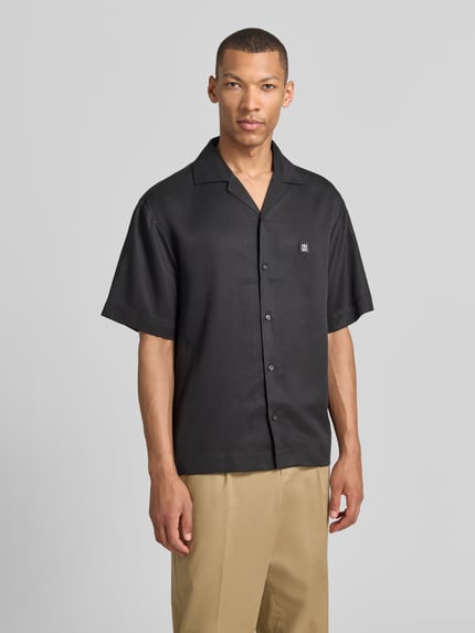 Männermodel trägt Relaxed Fit Freizeithemd aus reinem Lyocell Modell 'ESPINO' von HUGO, schwarz, Resortkragen, Nahaufnahme Oberkörper.