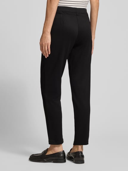 Frauenmodel trägt Hose aus Viskose-Mix mit elastischem Bund und Tunnelzug von Christian Berg Woman in Schwarz, glatte Textur, Ganzkörperansicht Rückansicht. Regular Fit, Stretch-Anteil, Bundweite 39 cm, Innenbeinlänge 68 cm.