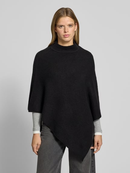 Frauenmodel trägt Poncho mit asymmetrischem Saum von PIECES, unifarben, Strick, hochgeschlossen, ärmellos, Ganzkörperansicht von vorne.