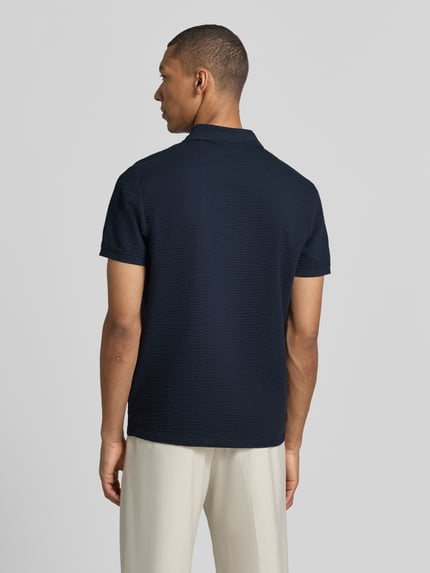 Männermodel trägt Regular Fit Poloshirt mit Strukturmuster von MCNEAL in Dunkelblau, Baumwoll-Mix, Reißverschluss, Kurzärmelig, Ganzkörperansicht Rückansicht.