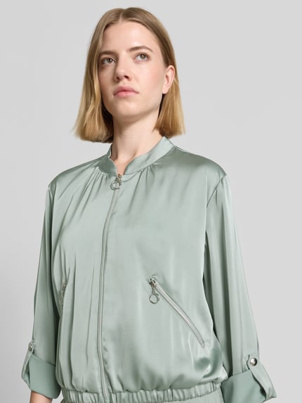 Vrouwenmodel draagt Blouson met verstelbare mouwlengte en ritszakken van Betty Barclay, satijn, regular fit, opstaande kraag, ritssluiting, kleur lichtgroen, borstwijdte 50 cm, schouderbreedte 38 cm, ruglengte 53 cm, mouwlengte 57 cm, Nahaufnahme bovenlichaam.