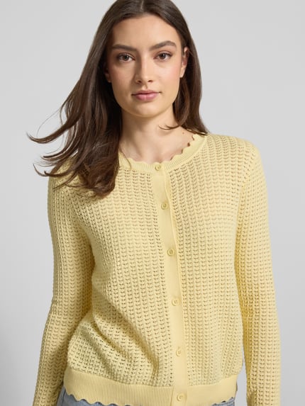 Modelka nosi kardigan rozpinany Regular Fit Strickjacke aus reiner Baumwolle Modell 'SCOUT' von Pieces, efekt: jednolity kolor, półprzezroczysty efekt, dzianina, zapięcie: listwa guzikowa, okrągły dekolt, długi rękaw, zakończenie rękawów i wykończenie: prążkowane, materiał: czysta bawełna, całkowite przetwarzanie dzianiny; półzbliżenie przód
