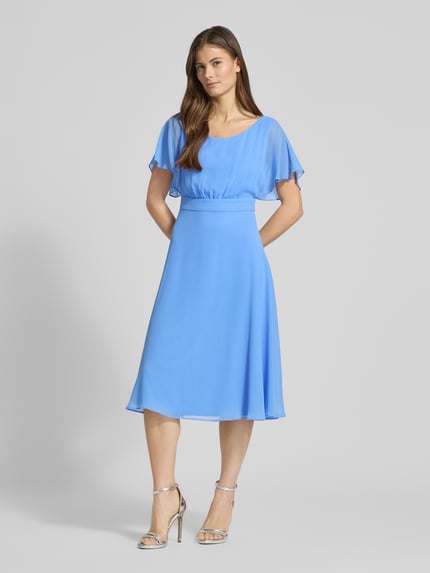 Vrouwenmodel draagt knielanges Kleid mit Rundhalsausschnitt van Vera Mont in lichtblauw, semi-transparant design, getailleerde fit, ronde hals, blinde ritssluiting, korte mouwen, ondoorzichtige onderjurk, ruglengte 102 cm, borstwijdte 37 cm, mouwlengte 27 cm, volledige vooraanzicht.
