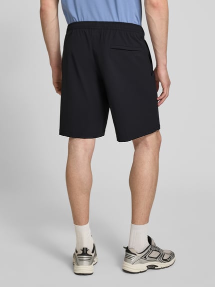 Männermodel trägt Regular Fit Sport-Shorts mit Label Print Modell 'TREVOL' von BOSS Green, Schwarz, elastischer Bund, Rückansicht Ganzkörperansicht.