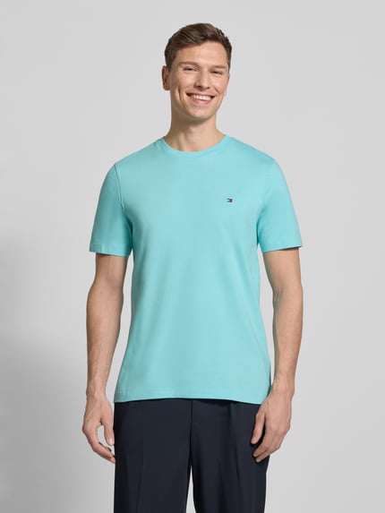 Männermodel trägt Regular Fit T-Shirt aus reiner Baumwolle von Tommy Hilfiger, Optik: Unifarben, Logo-Stitching, Rundhals, Jersey, Ganzkörperansicht von vorne.