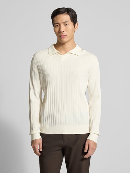 Männermodel trägt Loose Fit Poloshirt aus reiner Baumwolle Modell 'TORINO' von SELECTED HOMME in Creme, Rippstruktur, Ganzkörperansicht von vorne.