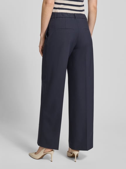 Frauenmodel trägt Wide Leg Stoffhose mit Bügelfalten von s.Oliver BLACK LABEL, Optik: Unifarben, elastischer Bund, angedeutete Gesäßtaschen, Ganzkörperansicht Rückansicht.