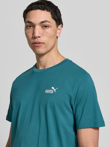 Männermodel trägt T-Shirt aus reiner Baumwolle von PUMA PERFORMANCE in Türkis mit Rundhalsausschnitt und Label-Stitching, Nahaufnahme Oberkörper