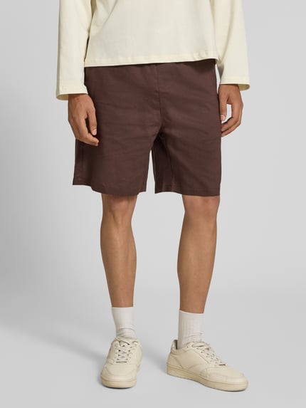 Männermodel trägt Leinenshorts mit elastischem Bund und Tunnelzug von ANOTHER COTTON LAB in Braun, Regular-Fit, Ganzkörperansicht von vorne.