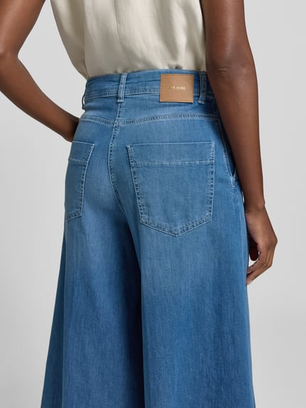 Kobiece modelka nosi Wide Fit Jeans in verkürzter Passform Modell 'Ella' od MAC z elastycznego bawełnianego materiału, jasnoniebieskie, widoczne tylne kieszenie, zapięcie na guzik i zamek, szerokość w rozmiarze 36: 41 cm, długość nogawki od wewnątrz w rozmiarze 36: 58 cm, ujęcie szczegółowe tyłu.
