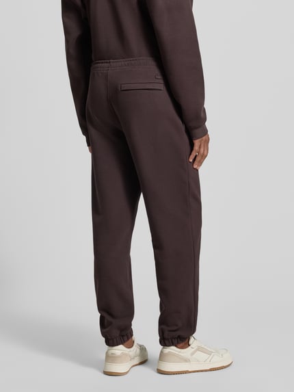 Männermodel trägt Regular Fit Sweatpants aus Baumwoll-Mix von Lacoste, Optik: Unifarben, Logo-Stitching, Ganzkörperansicht Rückansicht.