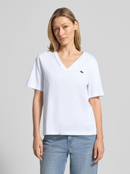Frauenmodel trägt Relaxed Fit T-Shirt aus reiner Baumwolle von Lacoste, Optik: Unifarben, Logo-Stitching, V-Ausschnitt; Ganzkörperansicht von vorne.