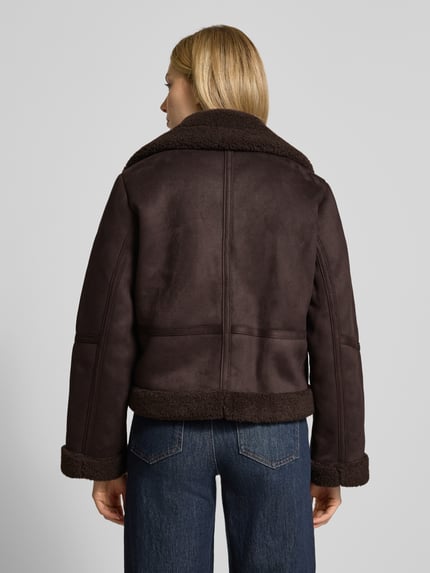 Frauenmodel trägt Regular Fit Kurtka w imitacji skóry z podszewką z futerka, Model 'HARPER' od Vero Moda, efekt: jednolity kolor, krój regular fit, kołnierz z połami, zapięcie na zatrzask, długi rękaw, wpuszczane kieszenie, wykończenie materiału: podszewka z futerka. Ganzkörperansicht Rückansicht.