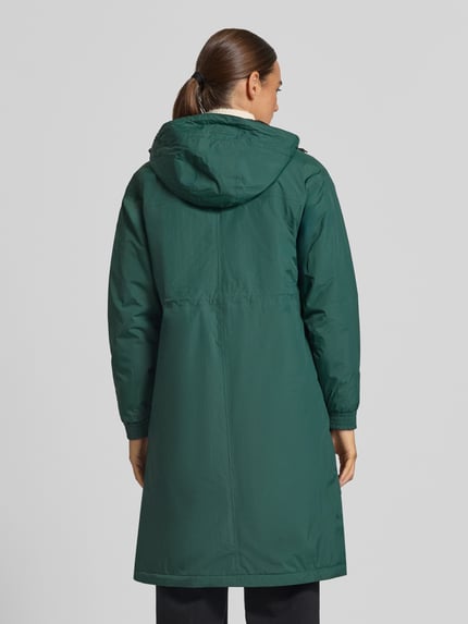 Frauenmodel trägt Regular Fit Mantel mit Logo-Print Modell 'DELIA' von K-WAY in Dunkelgrün, glatte Textur, Kapuze, Ganzkörperansicht Rückansicht. Mantel wasserdicht mit 10.000 Wassersäule, Rückenlänge 101 cm, Schulterbreite 51 cm, Brustweite 52 cm, Ärmellänge 57 cm.