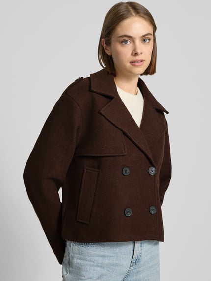 Frauenmodel trägt Regular Fit Jacke mit doppelter Knopfleiste von REVIEW in Dunkelbraun, Reverskragen, seitliche Eingrifftaschen, Ganzkörperansicht von vorne.