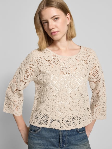 Frauenmodel trägt Relaxed Fit Pullover in Strick-Optik mit Allover-Pailettenbesatz von Betty Barclay im semitransparenten Baumwoll-Mix, beige, kurze Rückenlänge, langärmelig, gehäkelte Textur, Ganzkörperansicht von vorne.