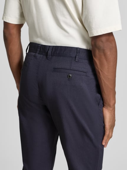 Männermodel trägt Slim Fit Stoffhose mit Viskose-Anteil van MCNEAL, donkerblauw met zakken, detailopname achteraan, context: heren stofhose, elastische mix, slim fit, steekzakken, achterzakken, knoop en rits, maat 50 taille 45 cm, binnenbeenlengte 82 cm