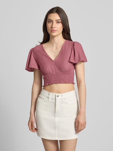 Frauenmodel trägt Regular Fit Crop Top mit Strukturmuster Modell 'HANNAH' von Only, Optik: Unifarben, gesmoktes Brustband, V-Ausschnitt, Schmetterlingsärmel, Kurzarm, Rumpfabschluss: Smok, Ganzkörperansicht von vorne.