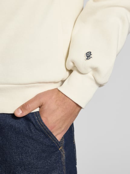 Männermodel trägt Sweatshirt mit Label-Print Modell 'FREDERIKSBERG' von JACK & JONES, cremefarbener Baumwoll-Mix, Nahaufnahme Oberkörper.
