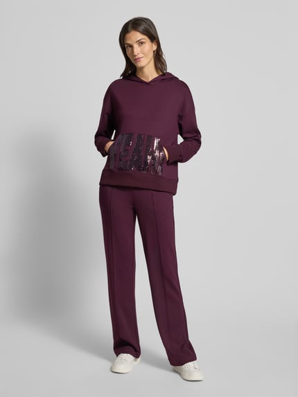 Frauenmodel trägt Hoodie aus Viskose-Mix mit Känguru-Tasche und Pailletten von Milano Italy, Relaxed-Fit, dunkles Lila, Ganzkörperansicht von vorne.