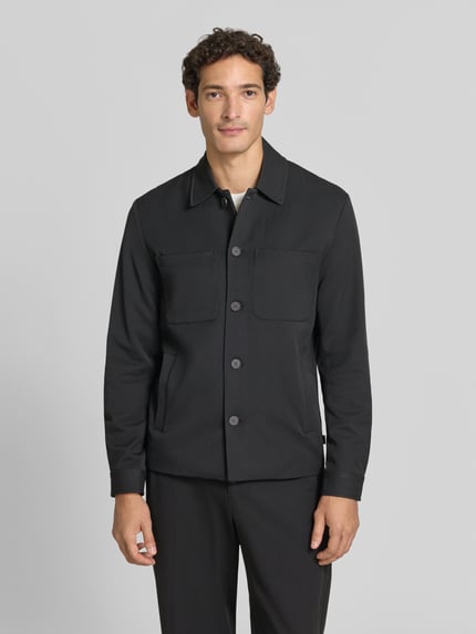 Männermodel trägt Hybrid Jacke mit Brusttaschen Modell 'Marseille' von Les Deux, Schwarz, Straight Fit, Ganzkörperansicht von vorne.