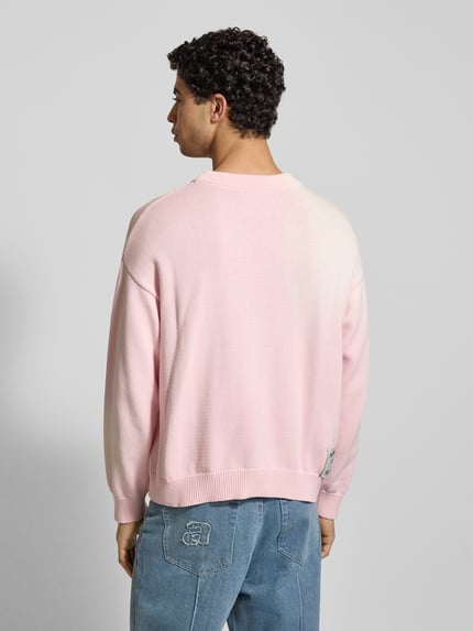 Männermodel trägt Strickpullover mit gerippten Abschlüssen von ANOTHER COTTON LAB in Hellrosa, Reine Baumwolle, Lockerer-Schnitt, Ganzkörperansicht Rückansicht.