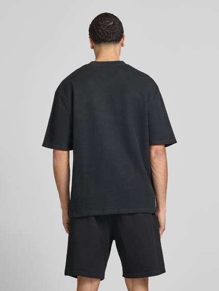 Männermodel trägt Oversized T-Shirt mit Strukturmuster von Pegador aus Baumwoll-Mix, oversized, Logo-Stitching, Rückenlänge 71 cm, Ganzkörperansicht Rückansicht