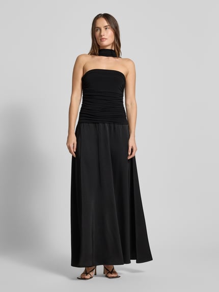 Frauenmodel trägt Abendkleid mit Raffungen Modell 'Hamina' von Neo Noir in Schwarz, A-Linie, Maxikleid, Material-Mix mit Stretch-Anteil, Ganzkörperansicht von vorne.