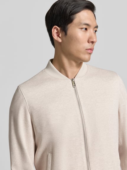 Männermodel trägt Blouson aus Viskose-Mix mit Zweiwege-Reißverschluss von Roy Robson in Beige mit Eingrifftaschen, Nahaufnahme Oberkörper. Regular-Fit, Stehkragen, Stretch-Anteil, Rückenlänge 68 cm, Schulterbreite 47 cm, Brustweite 59 cm, Ärmellänge 68 cm.
