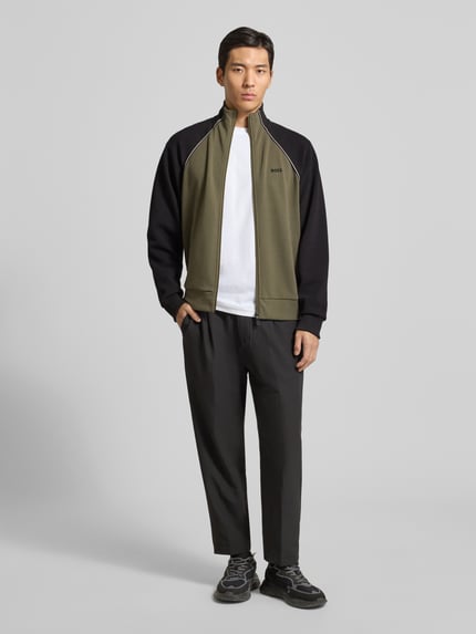 Männermodel trägt Regular Fit Sweatjacke aus Baumwoll-Mix von BOSS Green in Two-Tone-Optik mit Kontraststreifen, Ganzkörperansicht von vorne.