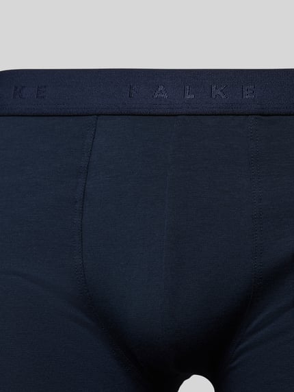 Männermodel trägt Trunks im 2er-Pack mit elastischem Logo-Bund von FALKE in Dunkelblau, glatte Struktur, Nahaufnahme Oberkörper. Baumwoll-Mix mit Stretch-Anteil, enganliegender Schnitt.