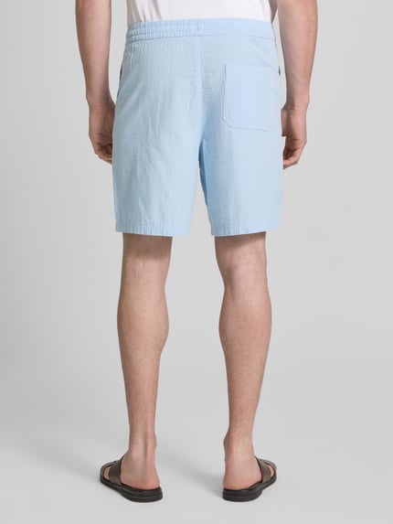 Männermodel trägt Regular Fit Shorts aus reiner Baumwolle Modell 'STUART' von SELECTED HOMME, Optik: Unifarben, Materialverarbeitung: Seersucker, Passform: Regular-Fit, Bundabschluss: elastisch, seitliche Eingrifftaschen, Gesäßtaschen, Ganzkörperansicht Rückansicht.