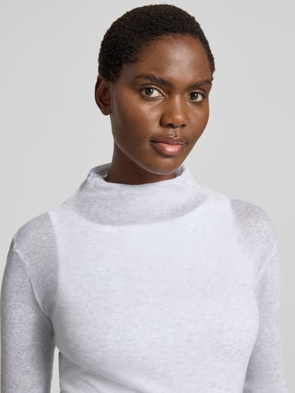 Vrouwenmodel draagt Slim Fit Rollkragenshirt uit puur katoen van American Vintage, siernaden, fijn geribd, met lange mouwen, Nahaufnahme bovenlichaam.