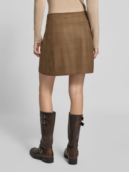 Frauenmodel trägt Minirock in Wickel-Optik Modell 'Kanille' von mbyM, brauner Material-Mix, A-Linie, Ganzkörperansicht Rückansicht.