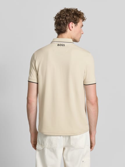 Męski model nosi Regular Fit Poloshirt aus Baumwoll-Mix model 'PADDY PRO' od BOSS Green, jasny beż, gładka tekstura, czarne lamówki, całkowity widok z tyłu.