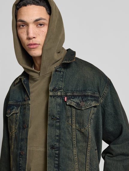 Mannenmodel draagt Relaxed fit Jeansjacke aus reiner Baumwolle Modell 'TRUCKER' van Levi's®, look: effen denim, borstzakken, labelstitching, knoopsluiting, puur katoen, nahaufnahme bovenlichaam.