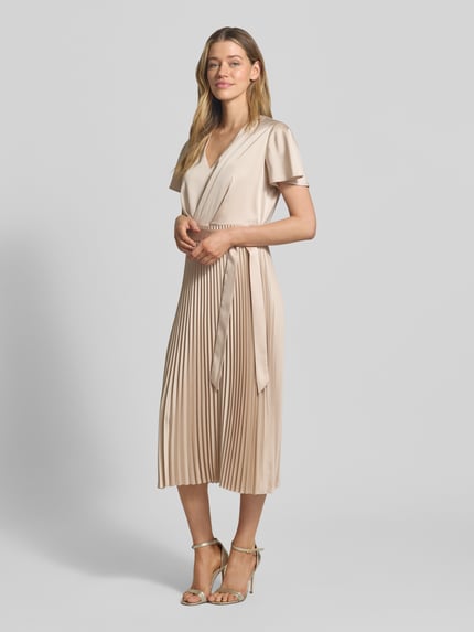 Frauenmodel trägt Midikleid mit Plisseefalten und V-Ausschnitt von comma in Beige, tailliert, Bindegürtel, Material-Mix, Ganzkörperansicht von vorne.