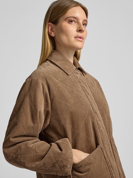 Frauenmodel trägt Kurzmantel mit Cordstruktur aus reiner Baumwolle Modell 'Hekordi' von OPUS, unifarben, Umlegekragen, verdeckte Knopfleiste, aufgesetzte Seitentasche, Nahaufnahme Oberkörper.