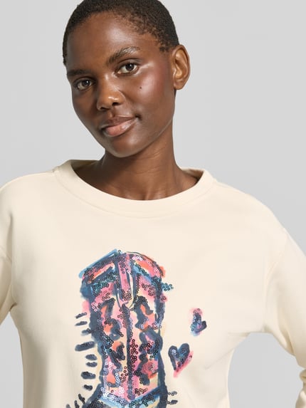 Vrouwenmodel draagt Sweatshirt met Motiv-Print en Pailletten van Milano Italy, katoenmix, relaxed fit, motiefprint, pailletten, ronde hals, detailopname bovenlichaam.